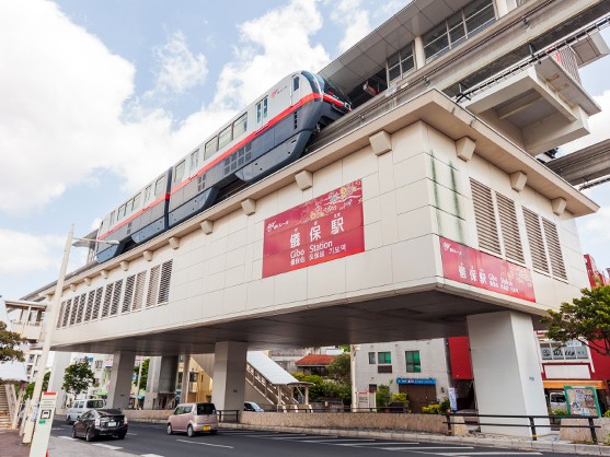 沖縄都市モノレール 儀保駅の駅舎と、高架を走るゆいレールの車両